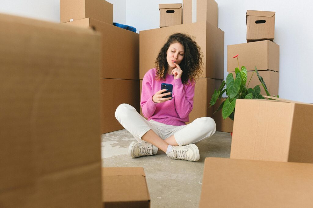 A woman is sitting on the floor and is surrounded by carton in the concept of choosing a good man and van in Clapham.