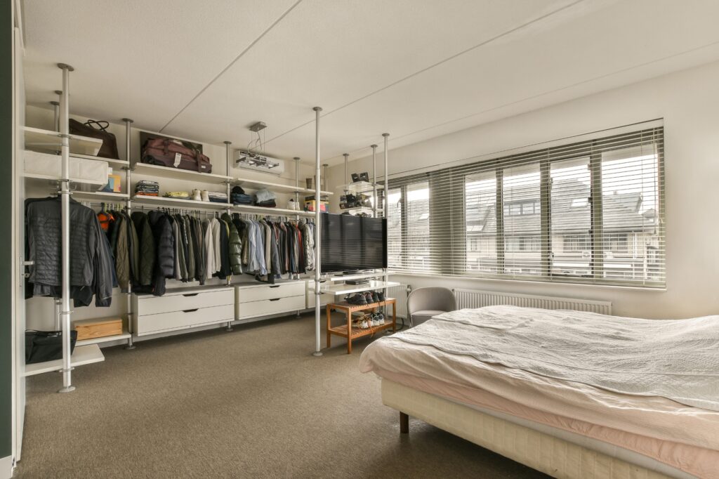 A spacious, tidy bedroom with organised clothes.